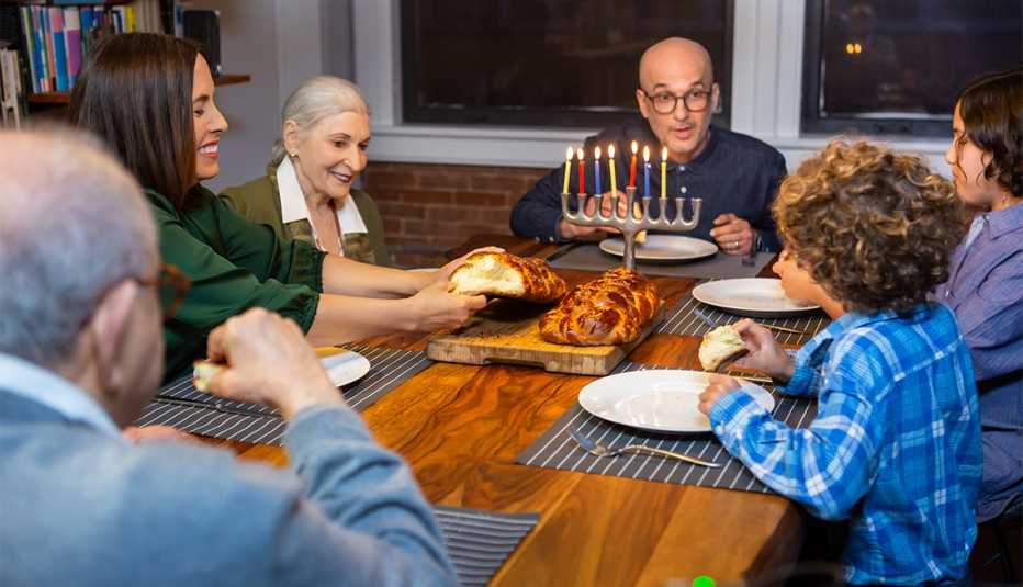 A mother tears challah while her family enjoys the Hanukkah festivities.