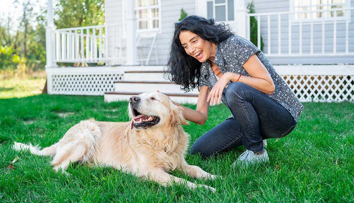Smiling woman playing with her golden retriever on front yard