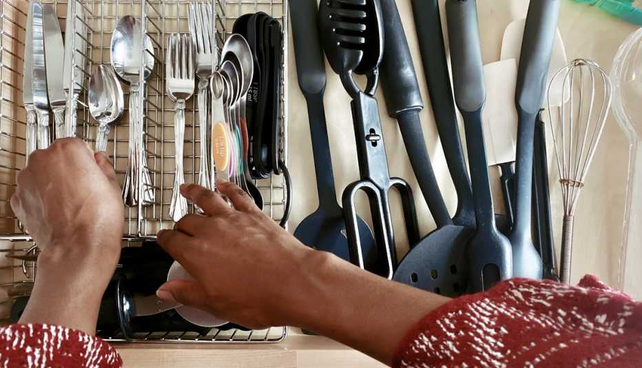 hands organizing cutlery in a kitchen drawer