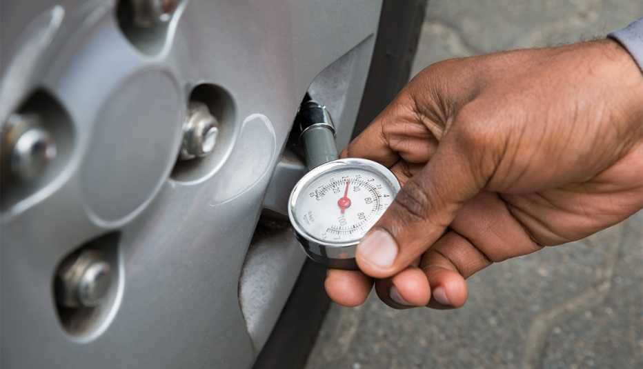 Close-up of person checking vehicle tire pressure
