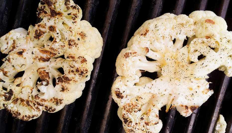 two cauliflower steaks cooking on a grill