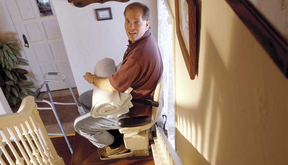 man sitting in stair lift chair at the bottom of stairs