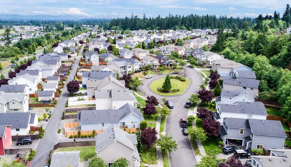 aerial view of a neighborhood with many houses, streets, trees and distant mountains