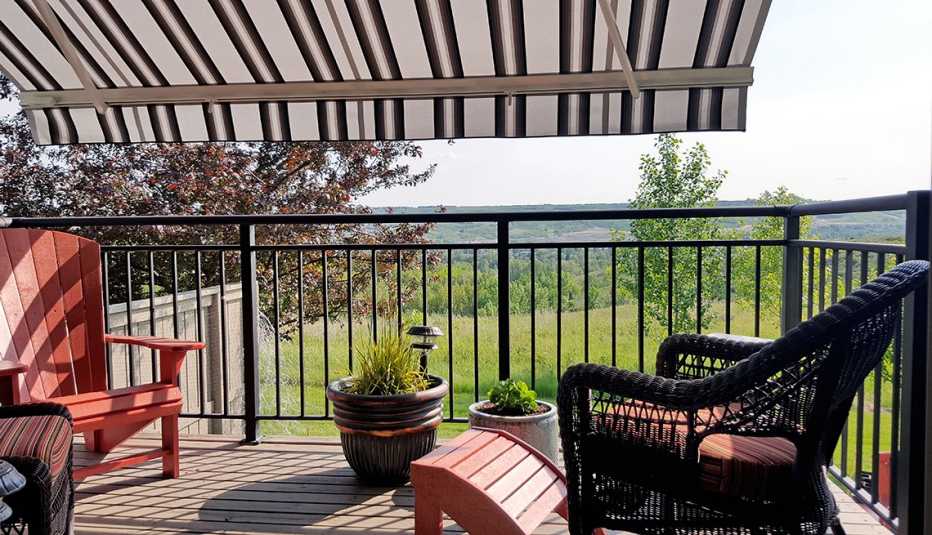 a comfortable deck with shade awning and chairs overlooking mountains and pasture 