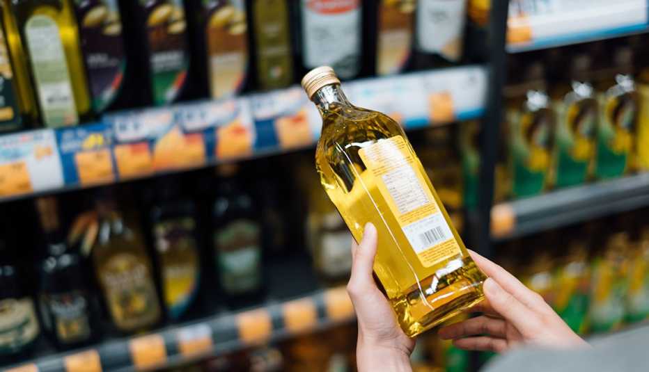 close up of someone holding a bottle of oil in a grocery aisle
