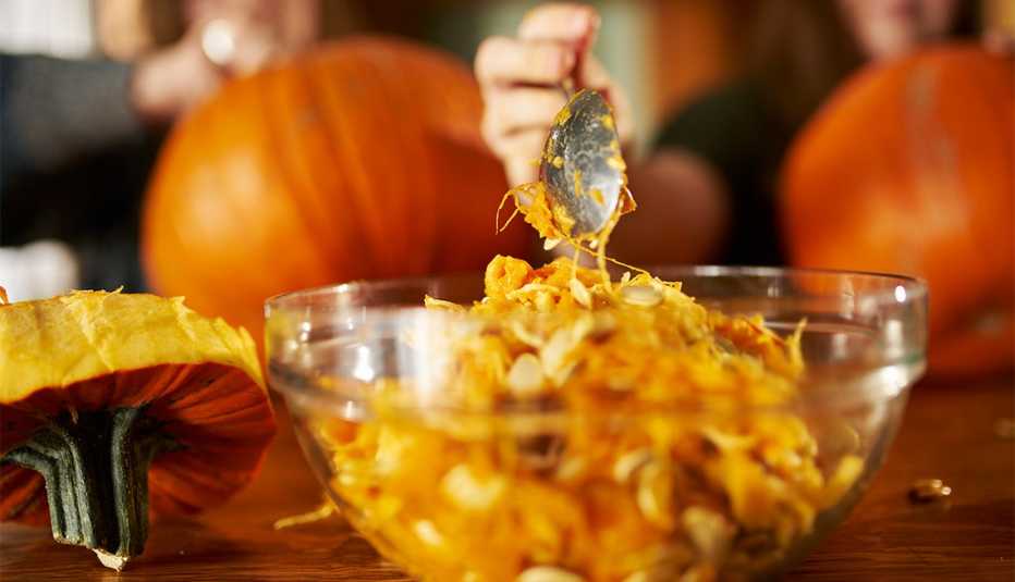 removing insides of pumpkin with spoon into bowl 