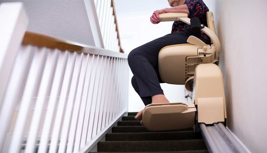 Woman sitting on stair lift at home 