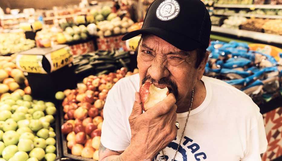 actor and chef danny trejo eating an apple in a gorcery store
