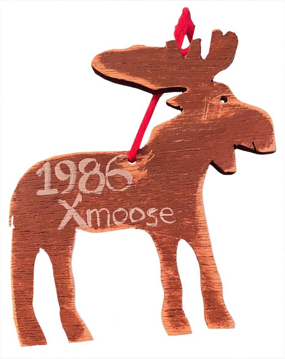 flat wooden tree ornament in the shape of a moose with the words nineteen eigthy six x mas moose written on it in marker or paint
