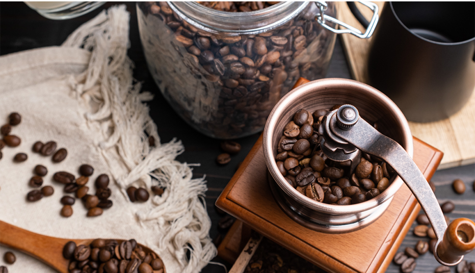 Roasted coffee beans in a glass jar and a coffee grinder