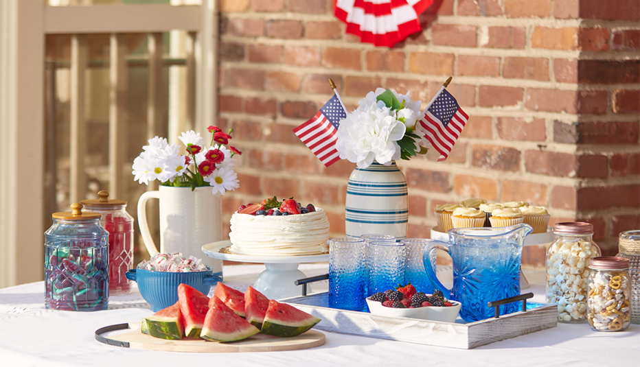 a table laid out with decorative fourth of july tablewear from dollar general such as a tray glasses a vase and flags