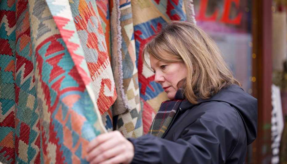a woman looking through rugs in a store