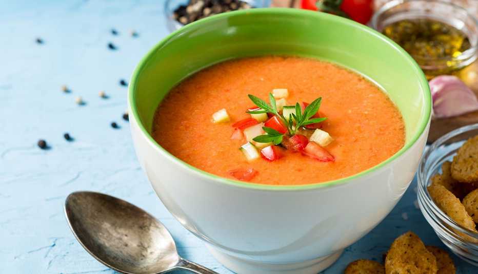 Summer cold soup gazpacho with parsley and vegetables on blue concrete background