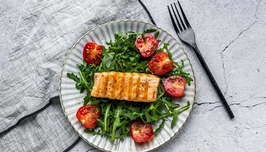 salmon salad on a white plate with cherry tomatoes