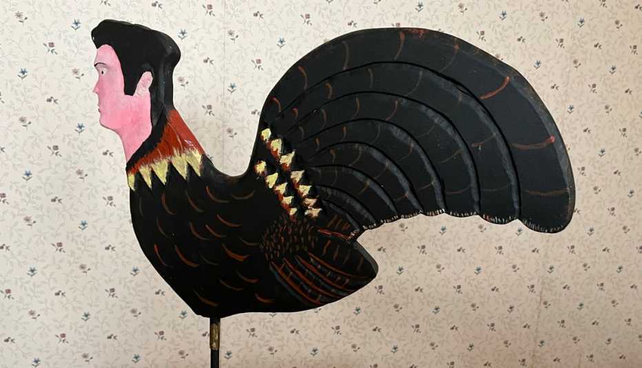 a wooden carving of a rooster with an elvis face