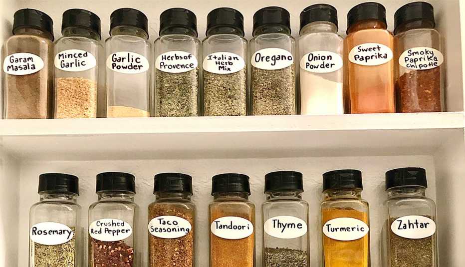 spices in clear jars with labels arranged neatly on a shelf in a cabinet
