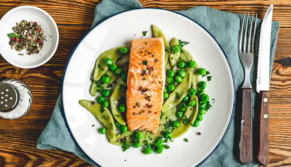 a dish of salmon over peas with salt and pepper