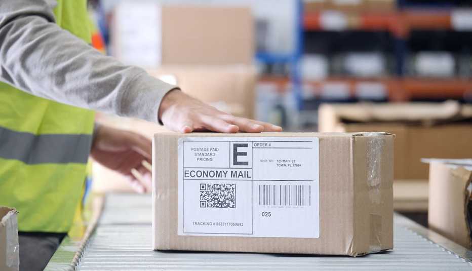 man handles a priority box on an assembly line in a mail distribution center