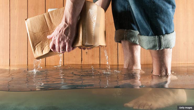 Man in flooded basement picking up a soaked box of papers