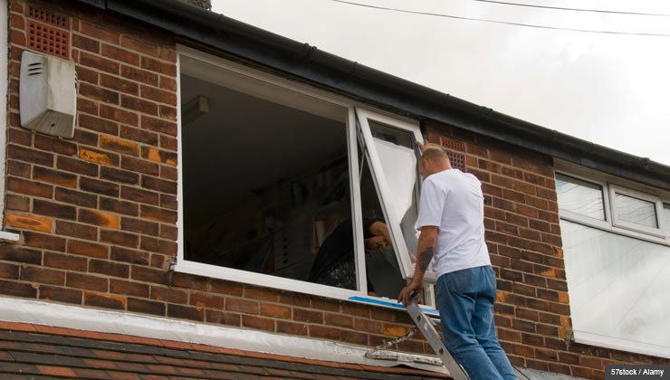 Man on ladder fixing windows