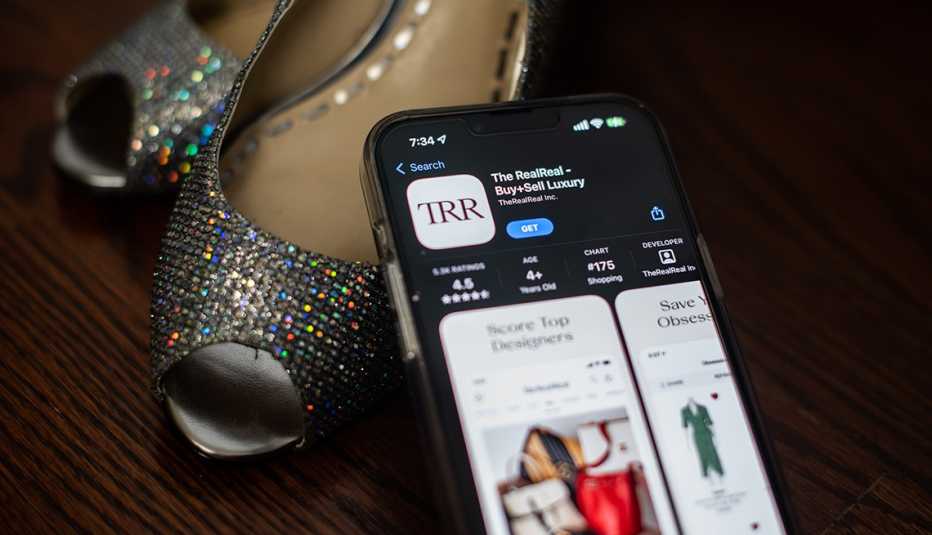 online thrift store shopping example of used dress shoes and a smart phone displaying the app for the RealReal platform