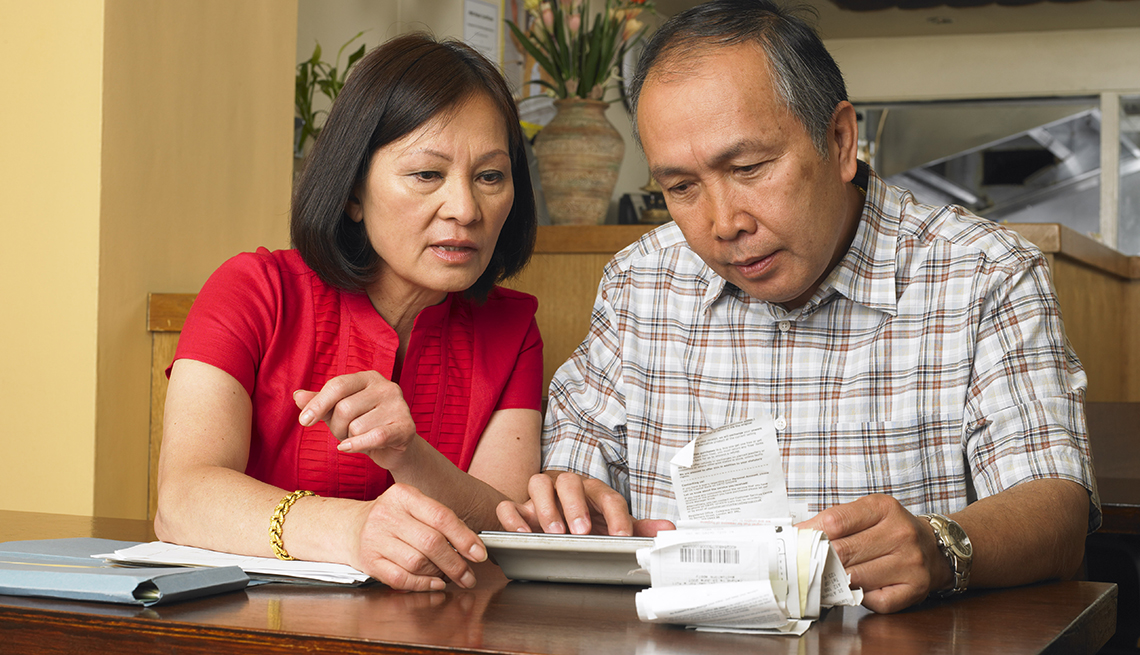 A couple sitting at a table reviewing receipts 