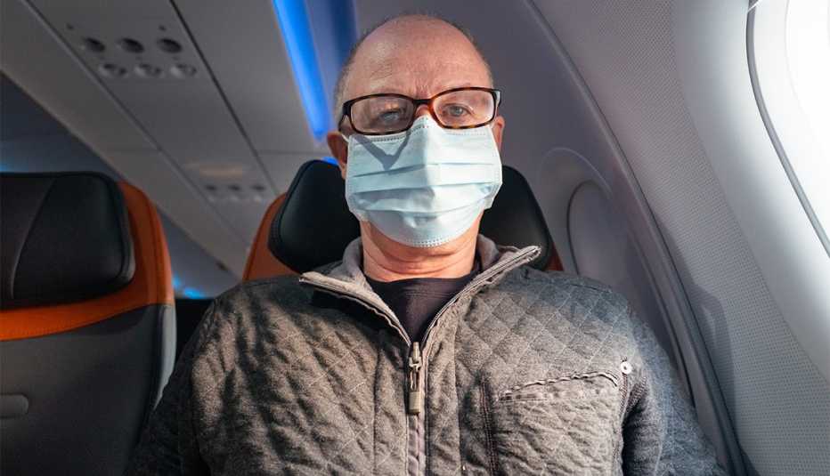 man sitting on a commercial jetliner, wearing protective mask 