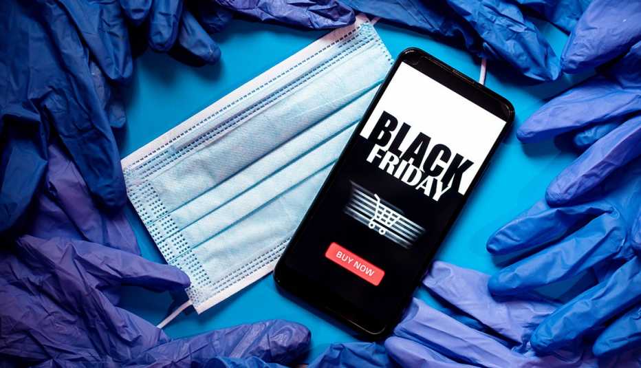 a smartphone displays an app for online shopping on Black Friday, surrounded by a covid mask and disposable gloves