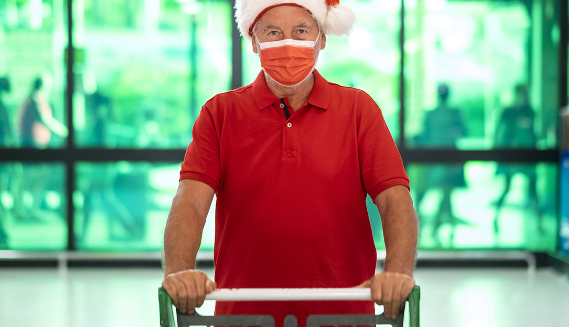 man with santa hat wearing a protective face mask due to covid-19 is pushing a shopping cart