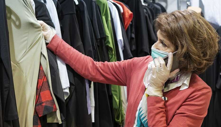 shopper looking at used clothes on a store rack while wearing mask and gloves during the coronavirus pandemic