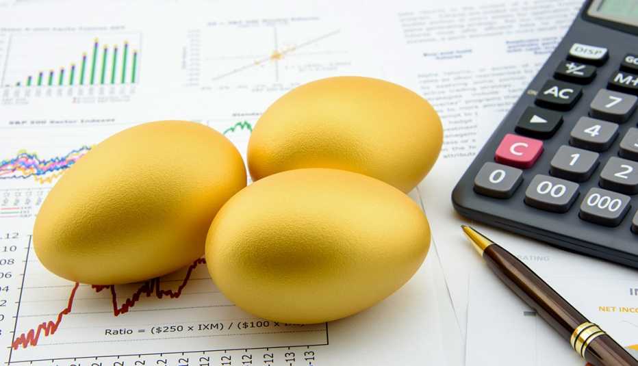3  golden eggs next to a calculator on financial reports