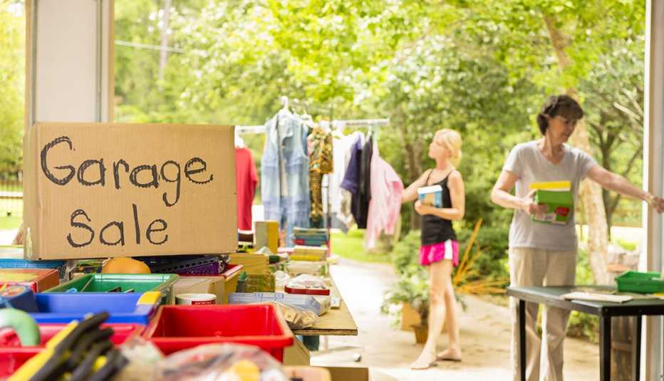 Summertime scene of shoppers browsing items at a home garage sale. 