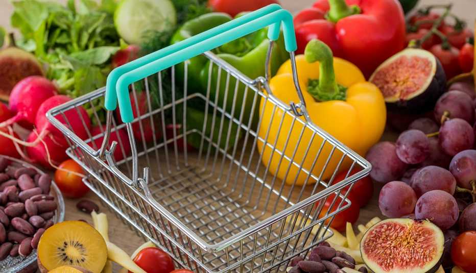 An empty shopping basket surrounded by assorted colorful grocery produce.