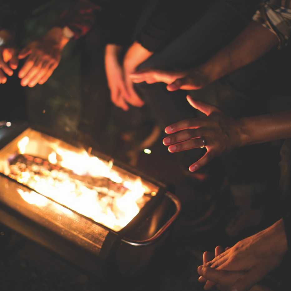 people warm their hands over a firepit