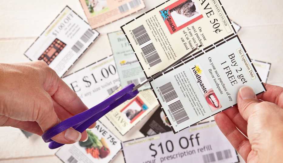 closeup of hands cutting coupons with scissors