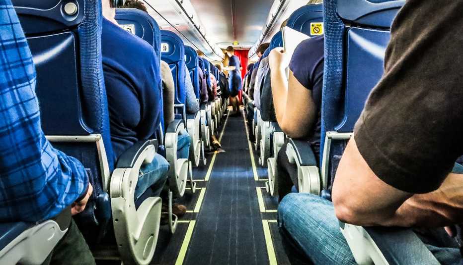 low angle shot of passengers seated in a crowded airplane and the center aisle