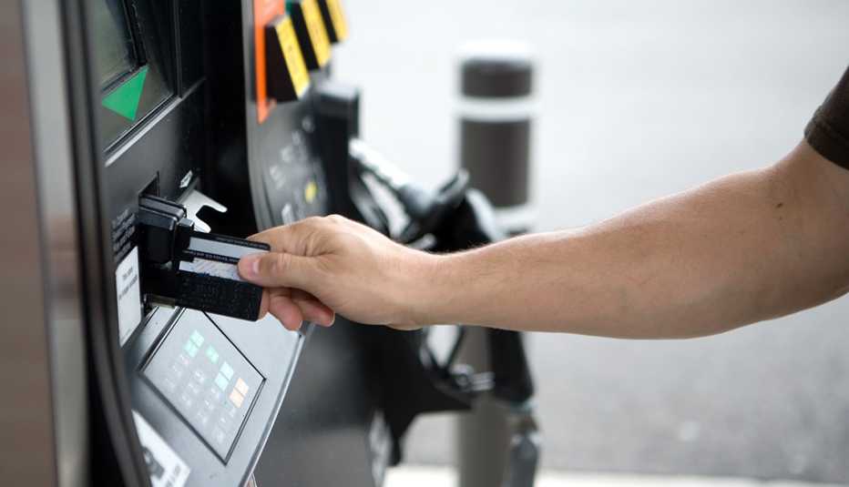 A man is inserting a credit card at a gas station pump