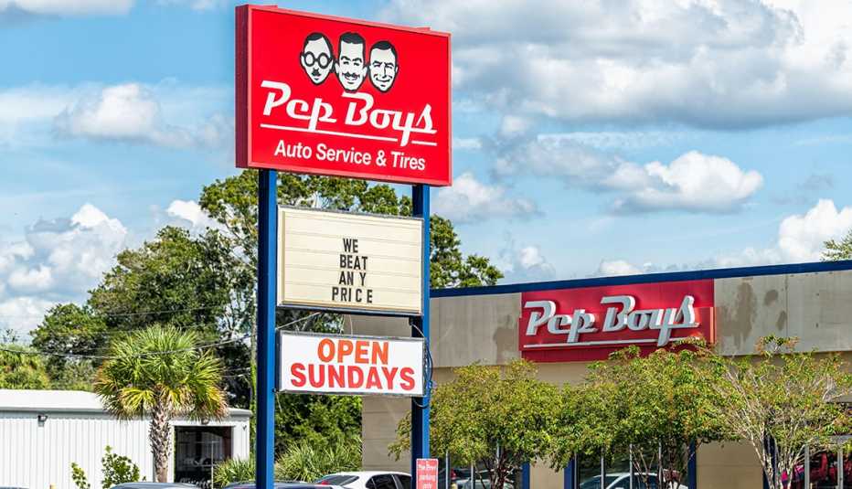 A freestanding Pep Boys sign with text that says "We Beat Any Price" outside a storefront of a Pep Boys auto service and tires store.