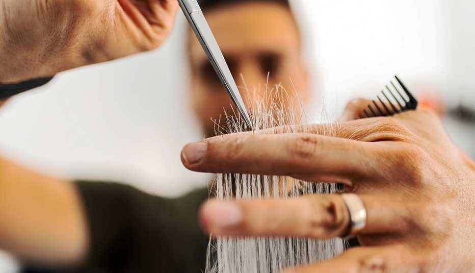 A hairstylist is trimming grey hair in a hair salon