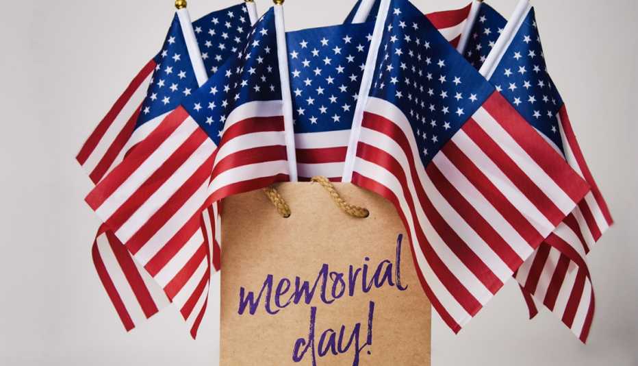brown paper shopping bag filled with small american flags and with the words memorial day sale printed on it
