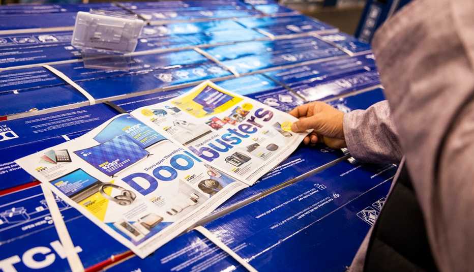 A Black Friday shopper looks over an advertisement of Doorbusters on sale at a Best Buy store