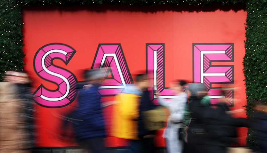people walking past a sale sign