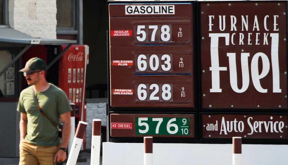 A customer walks by a gas station sign  that says Funace Creek Fuel, where fuel prices above $5 and $6 per gallon.
