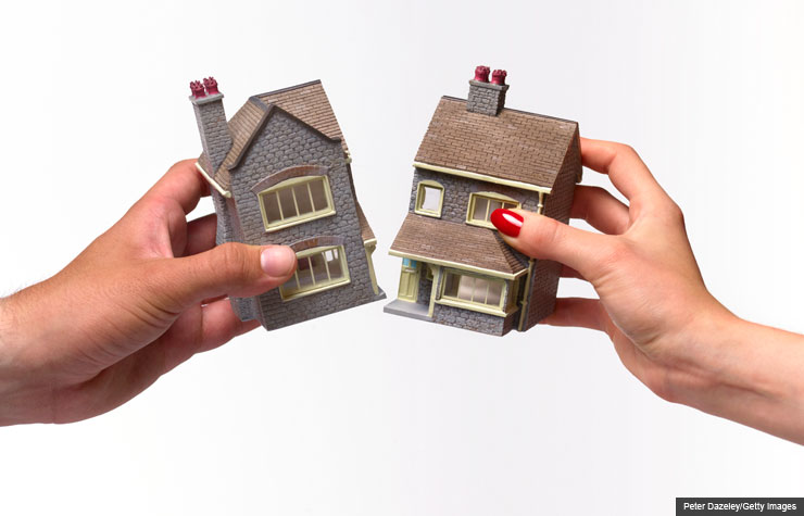 Man and woman holding toy house split in half.