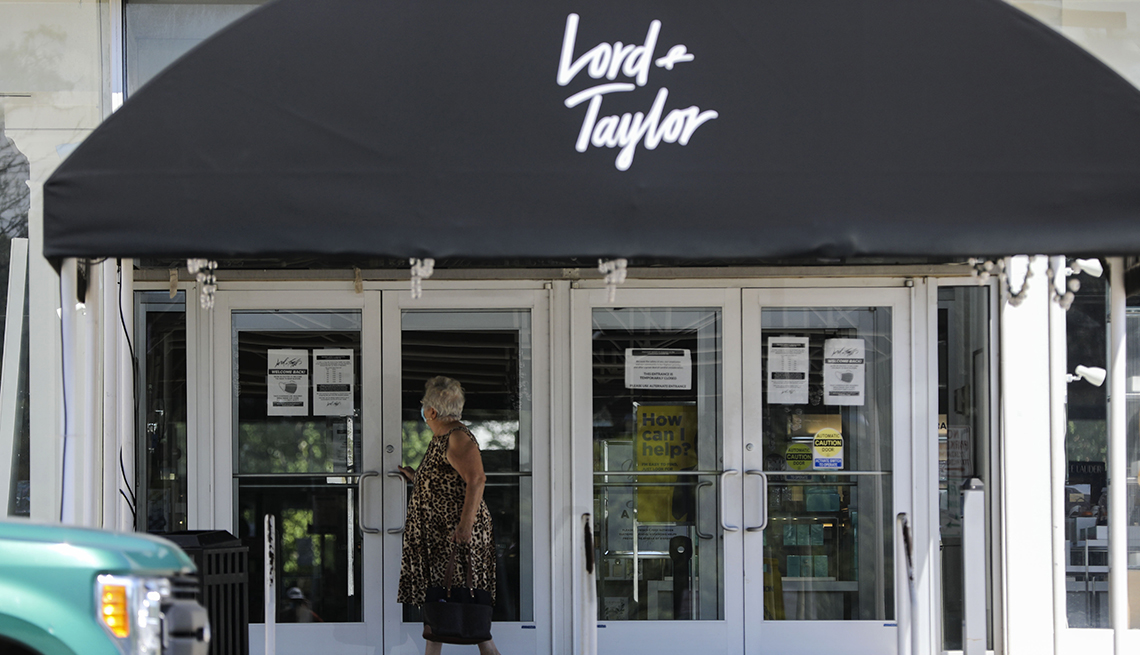 A woman looks at a notice in the front window of a Lord & Taylor department store, which is one of many retailers filing for bankruptcy protection amid the COVID-19 pandemic. 