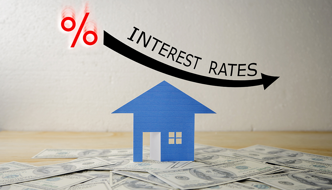 interest rates moving downwards illustrated by percentage sign, curved arrow, and a blue house standing on dollars  