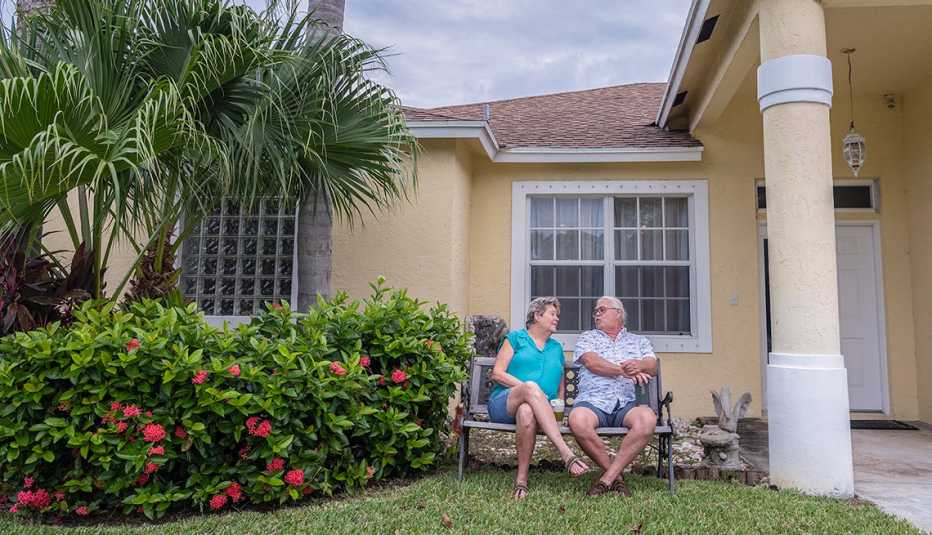 paula and dennis arntz sit on a bench in their front yard
