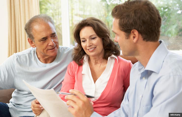 Senior couple at home with a financial advisor. (MBI/Alamy)