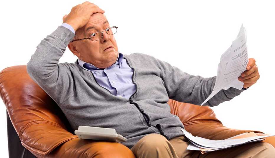 Shocked man looking at his bills in disbelief, mutual fund capital gains trap 