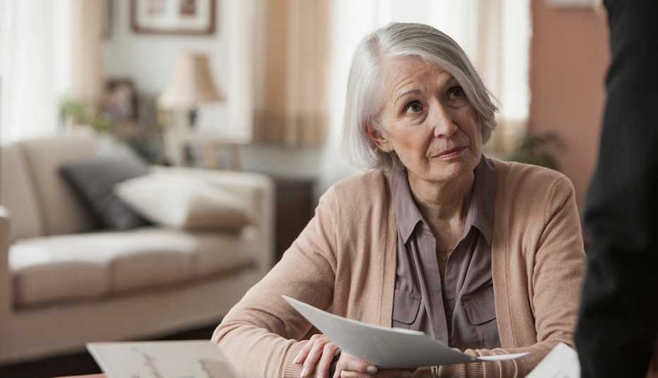Mature woman holding paperwork looking concerned